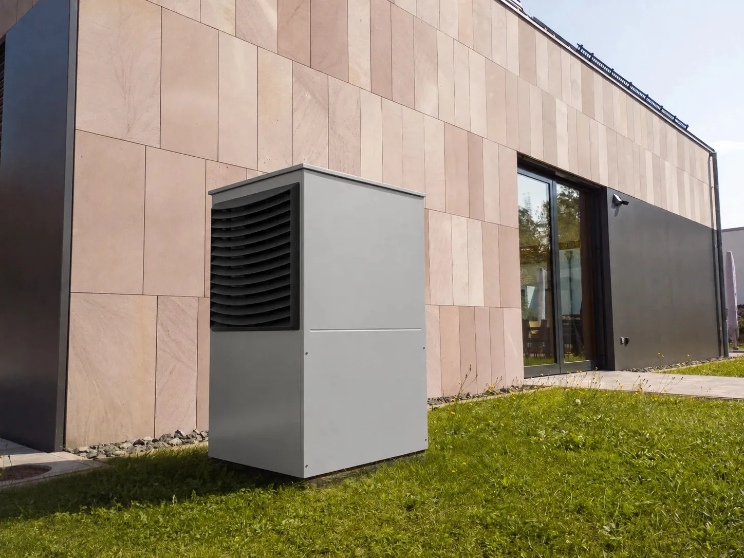 Outdoor air-source heat pump unit installed beside a house façade