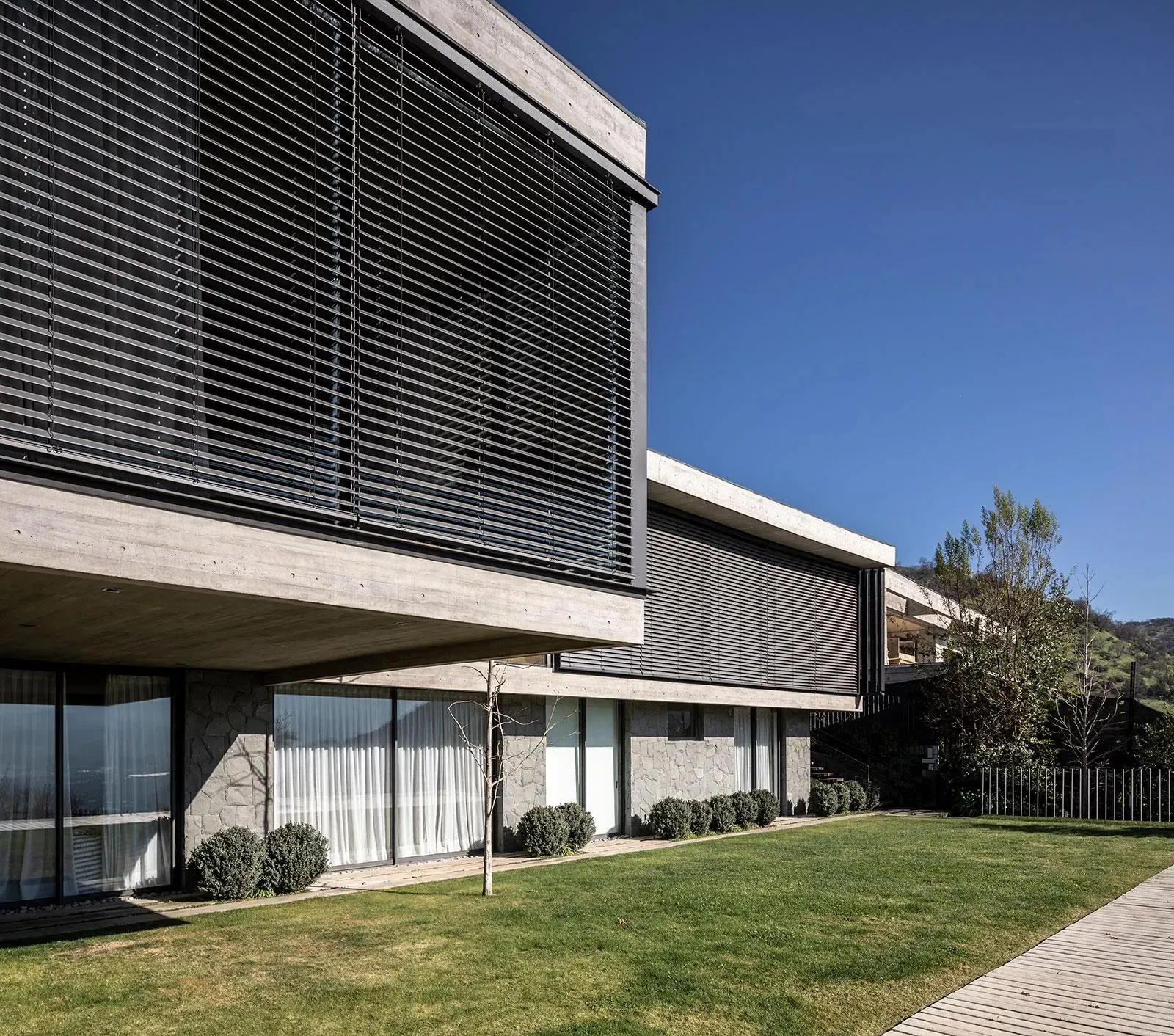 Modern house with a large motorised external louvre blind extended over a window façade